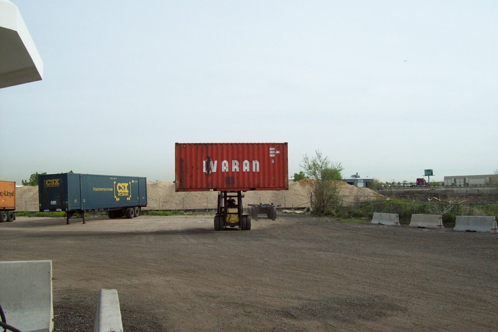 A forklift transporting a red shipping container